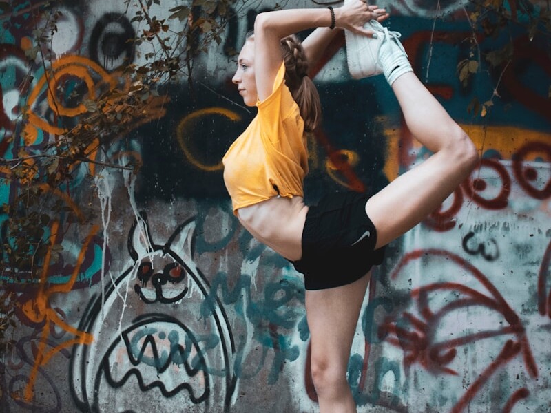 woman in yellow shirt and black shorts standing near wall with graffiti