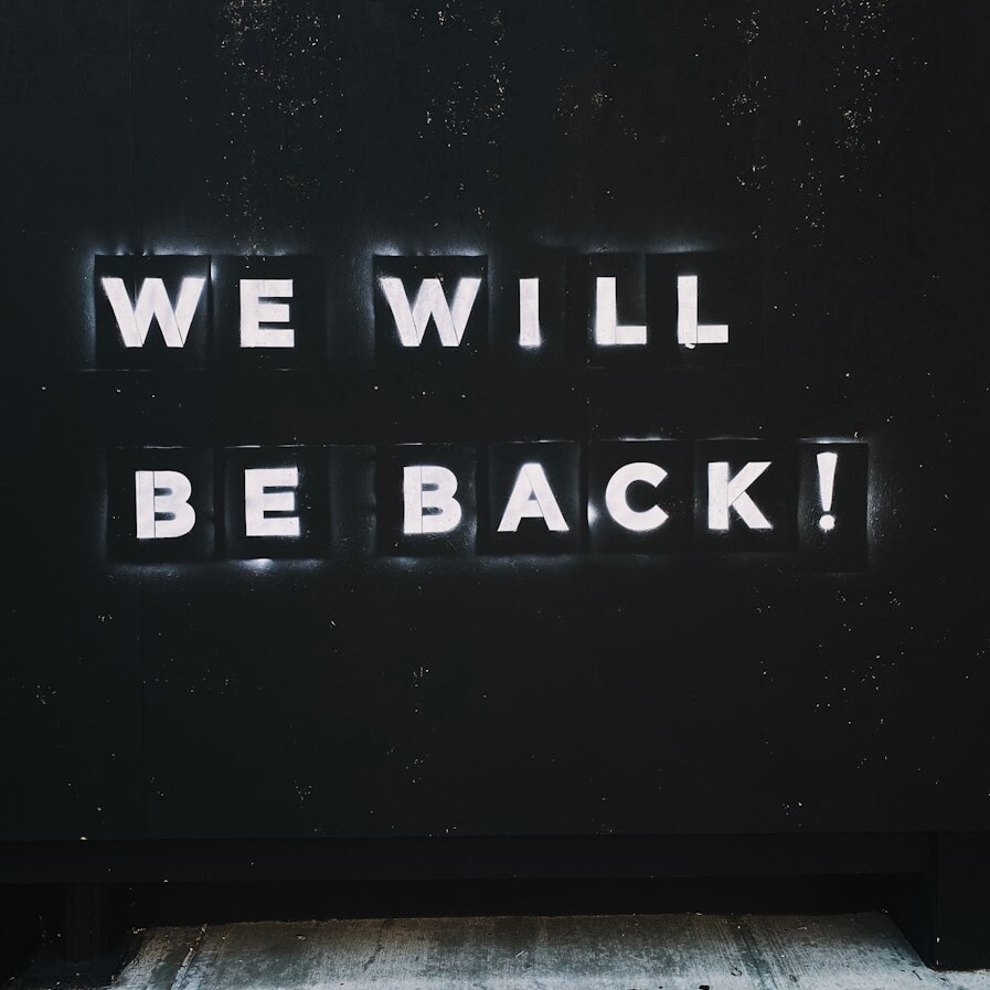 a sign that says we will be back on the side of a building