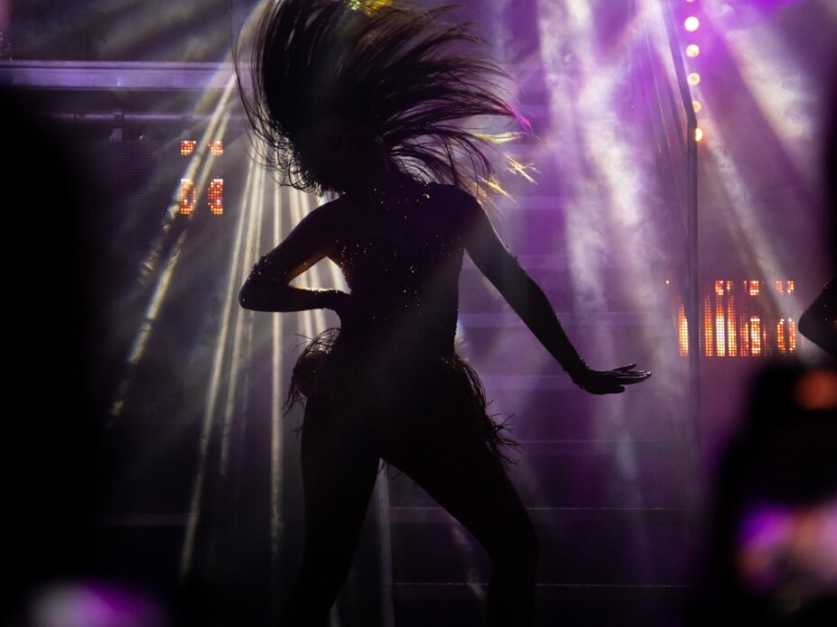 a woman is dancing on stage with lights behind her